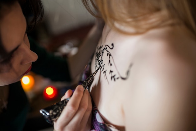 Close-up van een vrouw die een heena-tatoeage van vrouwelijke artiest maakt