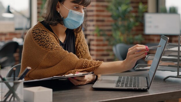 Close-up van een vrouw die papieren en laptop gebruikt om aan bedrijfsstrategie en project te werken. Ondernemer die met computer en documenten werkt, marketingplan met technologie ontwerpt.