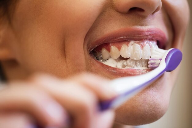 Close-up van een vrouw die tandenborstel gebruikt terwijl ze haar tanden schoonmaakt
