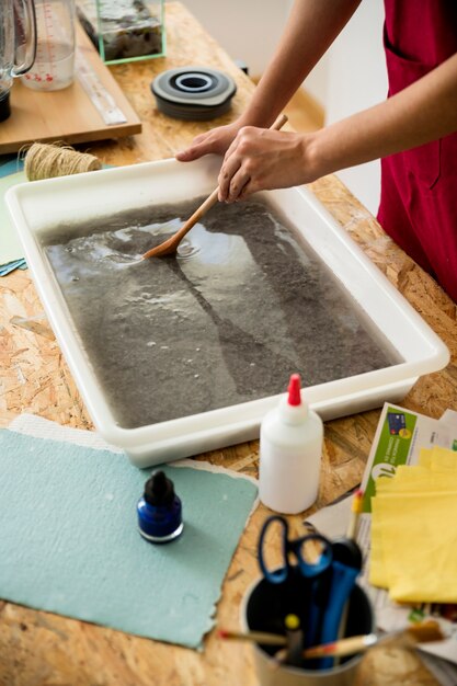 Close-up van een vrouwelijke hand roeren papierpulp in lade over houten bureau