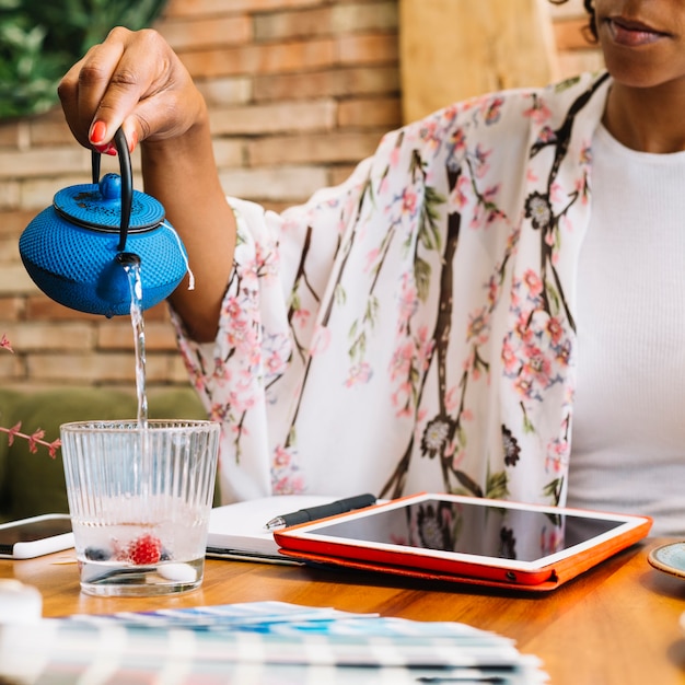 Gratis foto close-up van een vrouwen gietend water in het transparante glas