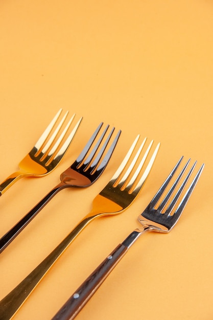 Close-up van elegante glanzende RVS vorken op geïsoleerde gouden achtergrond met vrije ruimte