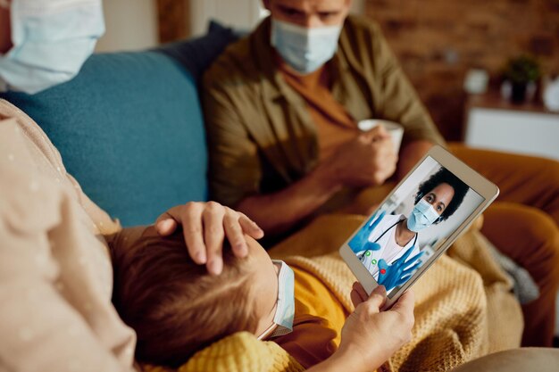 Close-up van familie die videogesprek voert met zwarte vrouwelijke arts als gevolg van een pandemie van het coronavirus