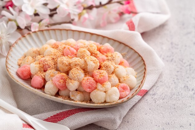 Close up van gefrituurde rode en witte tangyuan (tang yuan, kleverige rijst knoedel ballen) met pinda poeder op grijze tafel achtergrond voor winterzonnewende festival voedsel.
