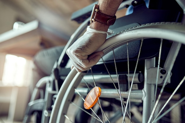 Close-up van gehandicapte zakenman die beschermende handschoenen draagt terwijl hij zichzelf in een rolstoel duwt