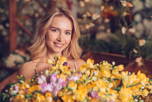 Close-up van gele bloemen boeket voor blonde jonge vrouw op zoek naar camera