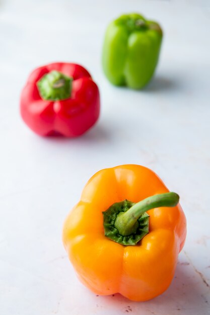 Close-up van gele peper met andere paprika's op wit