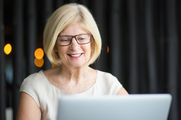 Close-up van glimlachende senior vrouw werken op laptop