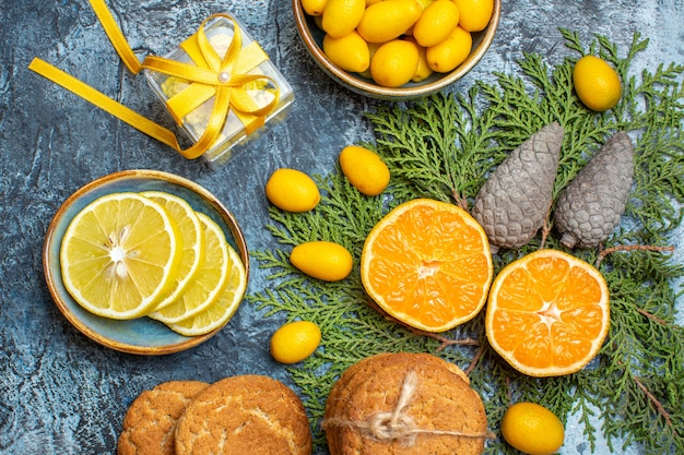 Close-up van halve en hele verse citrusvruchten en gele geschenkdoos conifer kegels heerlijke koekjes op donkere achtergrond