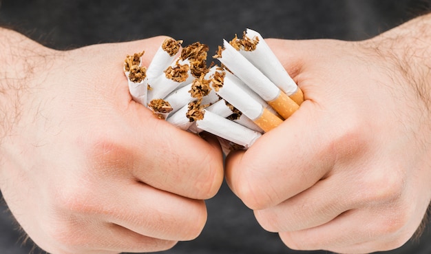 Gratis foto close-up van handen die bundel sigaretten breken