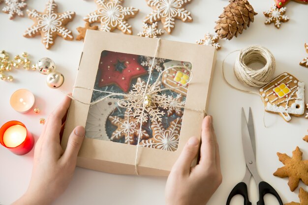 Close-up van handen met een feestelijke doos met kerstkoekjes