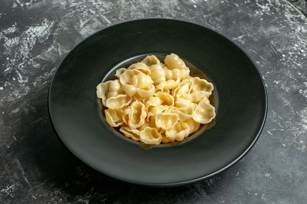 Close-up van heerlijke conchiglie op een zwarte plaat op grijze achtergrond