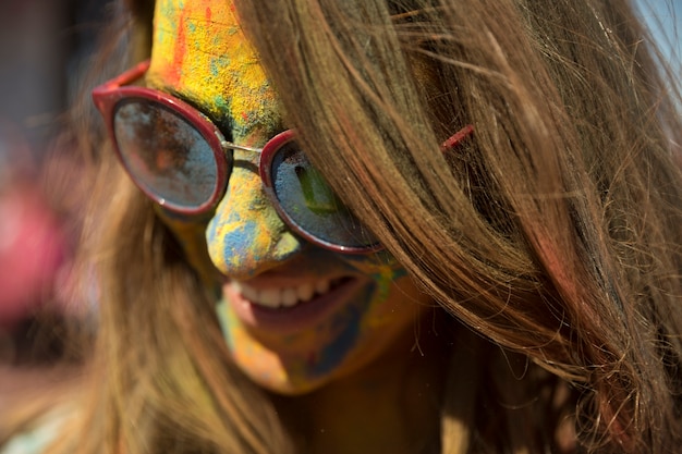 Gratis foto close-up van het gezicht van de vrouw bedekt met holi kleur dragen van een bril