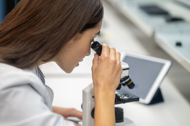 Close-up van het gezicht van de vrouw die door de microscoop kijkt