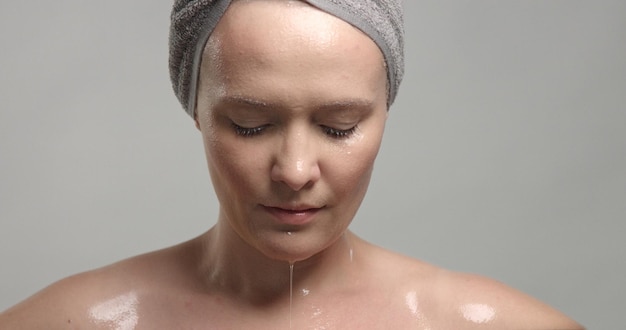 Close-up van het gezicht van de vrouw met natte huid met druppels water erop Mousturizing skin concept