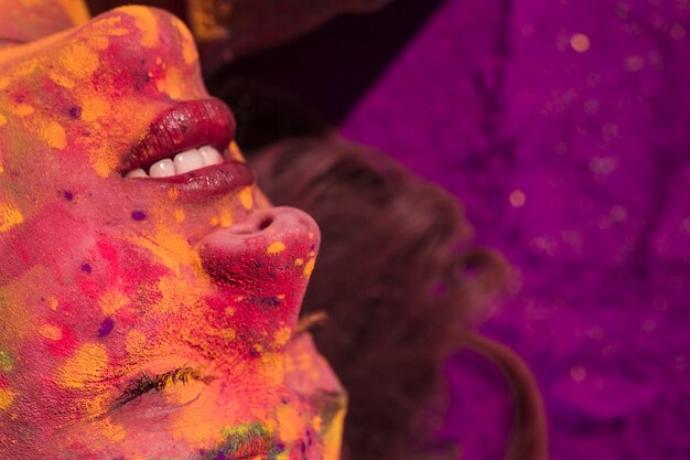 Close-up van het gezicht van een vrouw bedekt met holi kleur