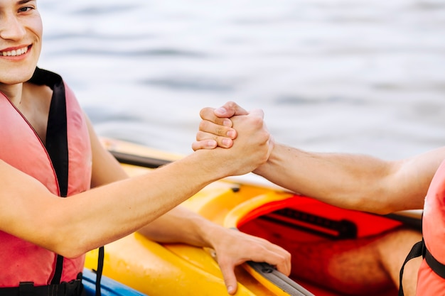 Gratis foto close-up van het glimlachen van mannelijke kayaker holdingsvrienden hand