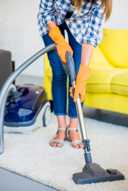 Close-up van het hand schoonmakende tapijt van een vrouw met stofzuiger