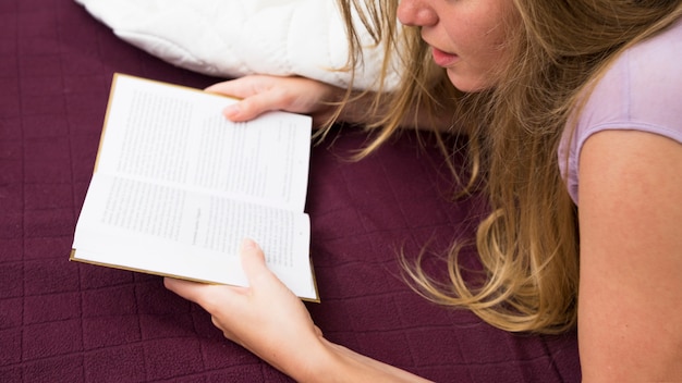 Gratis foto close-up van het jonge boek van de vrouwenlezing op bed