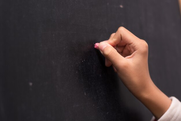 Close-up van het recht van de hand te schrijven op een schoolbord