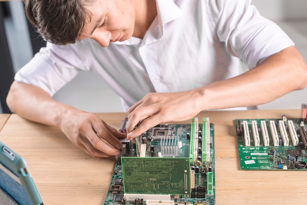 Close-up van IT mannelijke technicus die het computer mainboard herstelt