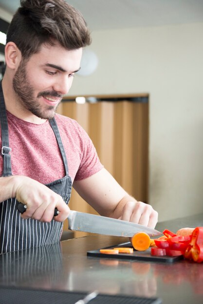 Close-up van jonge man snijden plakjes wortel met een scherp mes