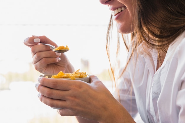 Close-up van jonge vrouw die cornflakes met lepel eet