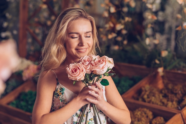 Close-up van jonge vrouw die de roze rozen ruikt