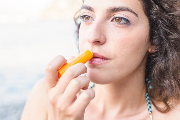 Close-up van jonge vrouw die lippenpommade toepast