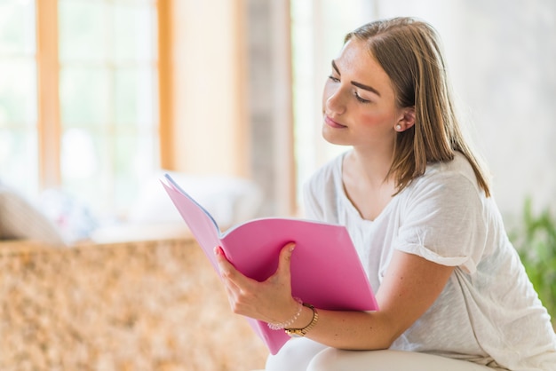 Close-up van jonge vrouw die roze dekkingsboek houdt