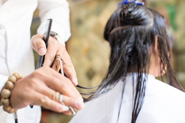 Close-up van kappers hand snijden vrouwelijk haar