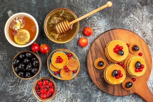 Close-up van klassieke pannenkoeken op snijplank met honing en fruit