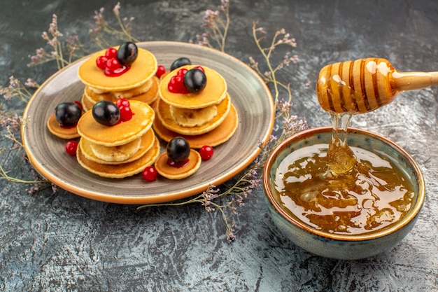 Close-up van klassieke zelfgemaakte pannenkoeken en honing op grijs