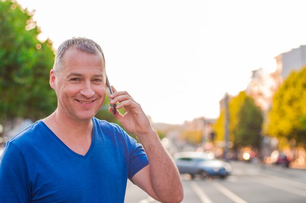 Close-up van knappe aantrekkelijke serieuze geconcentreerde krullend knappe mannelijke praten op de mobiele telefoon