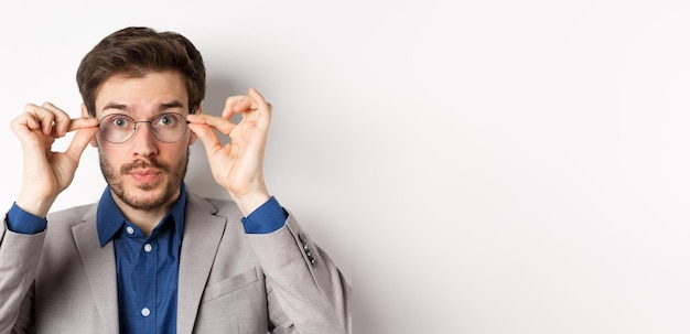 Gratis foto close-up van knappe man in pak proberen nieuwe bril op witte achtergrond te zetten
