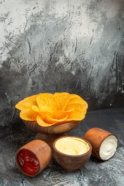 Close-up van knapperige aardappelchips ingericht als bloemvormige mayonaise en ketchup op grijze tafel