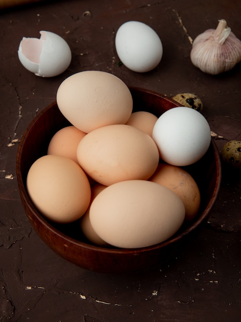 Gratis foto close-up van kom vol eieren met knoflook op kastanjebruine bakground