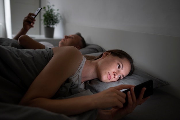 Gratis foto close-up van koppel op telefoons in slaapkamer