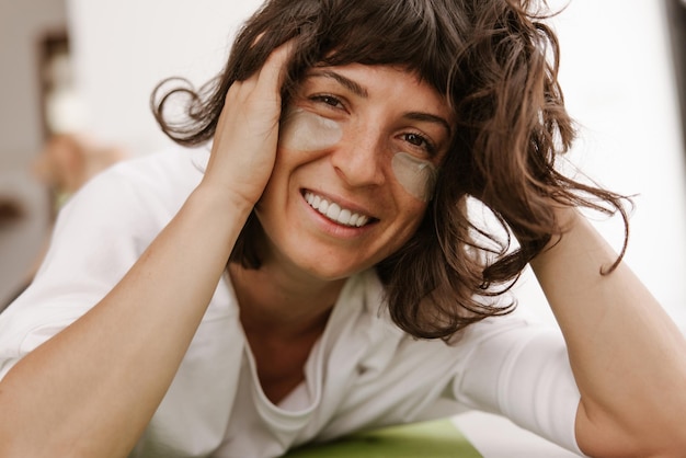 Gratis foto close-up van lachende vrouw met groene ogen patches thuis