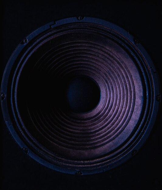 Close-up van luidsprekermembraan op zwarte achtergrond met gekleurde verlichting.