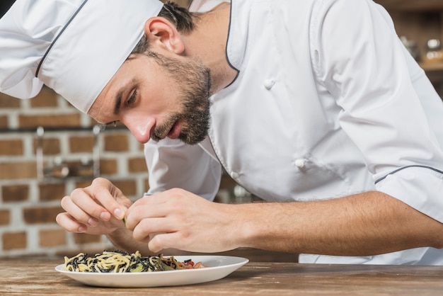 Gratis foto close-up van mannelijke chef-kok die de spaghettischotel voorbereidt