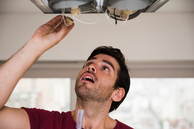 Gratis Foto close-up van mannelijke elektricien die houder van plafondlicht installeert