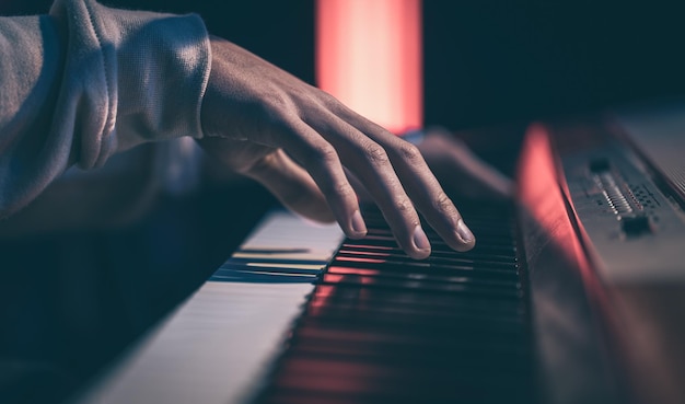 Close-up van mannelijke handen die de pianotoetsen spelen