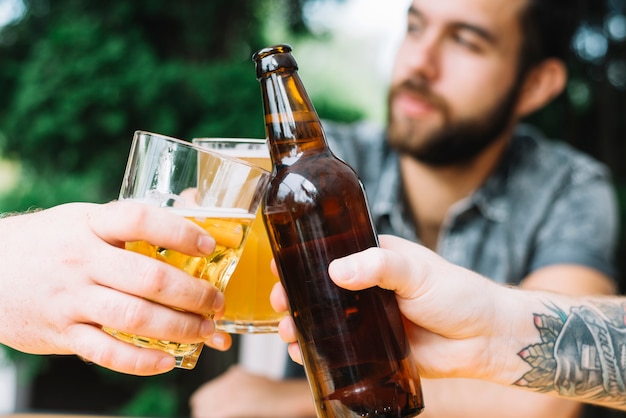 Close-up van mannelijke vrienden die met alcoholische dranken in openlucht toejuichen