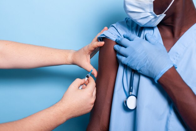 Close-up van medisch verpleegkundige die wordt gevaccineerd door arts