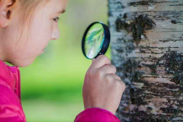 Close-up van meisje op zoek met vergrootglas een kofferbak