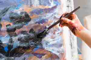 Gratis foto close-up van menselijke hand schilderij op doek met penseel
