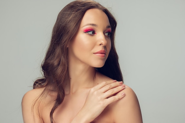 Close up van mooi vrouwelijk gezicht, lippen met lichte stijlvolle make-up geïsoleerd op grijs