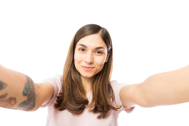 Close-up van mooie jonge vrouw die selfie neemt en glimlacht op witte achtergrond