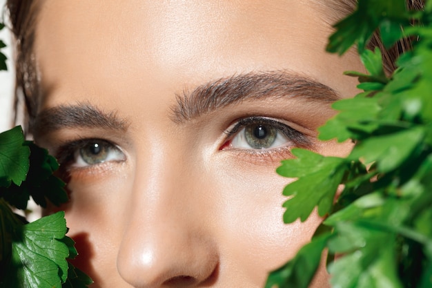 Close up van mooie vrouwelijke gezicht met biologische behandeling op wit.